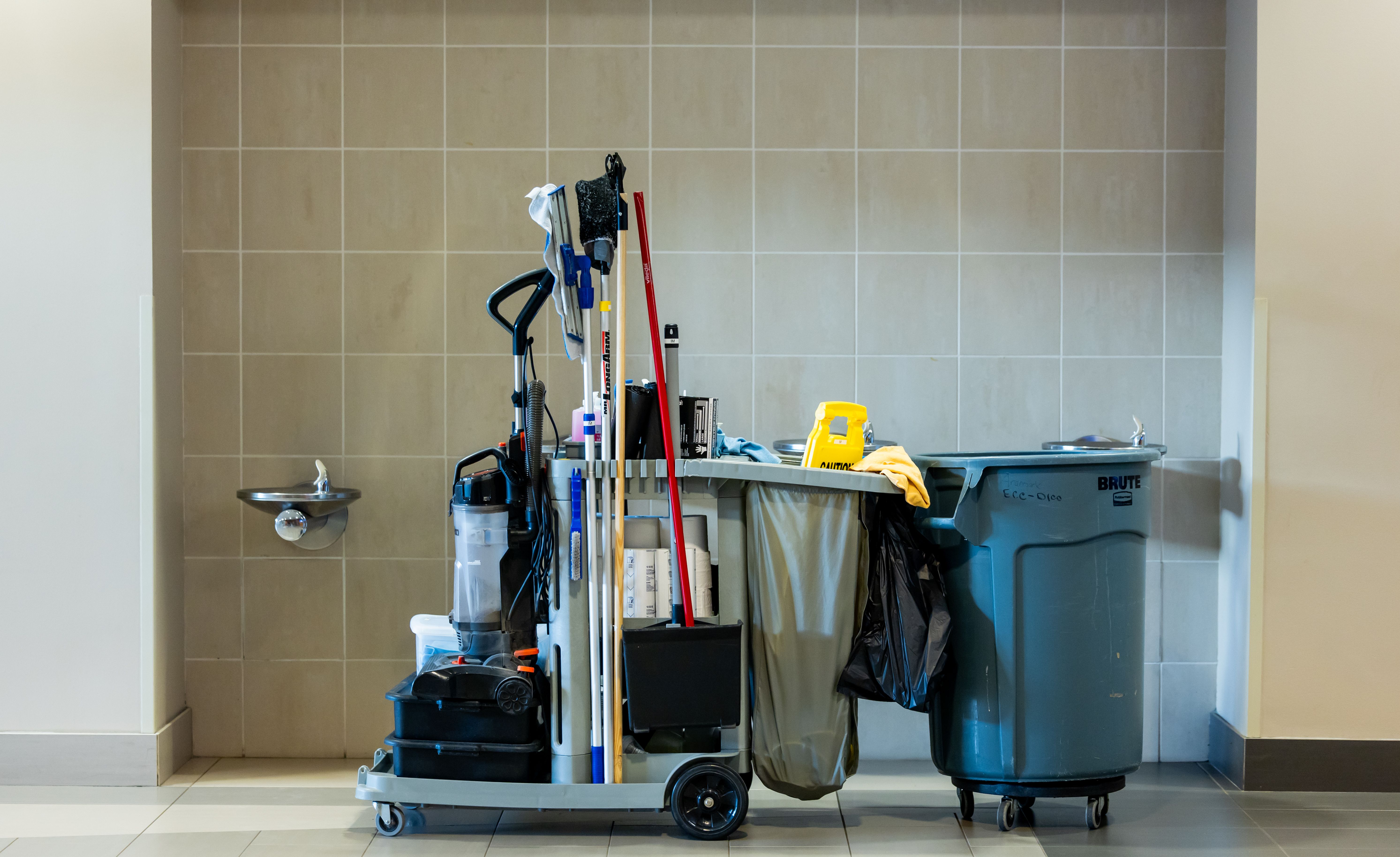 Professional cleaning equipment cart with mops, a vacuum and supplies in a commercial building
