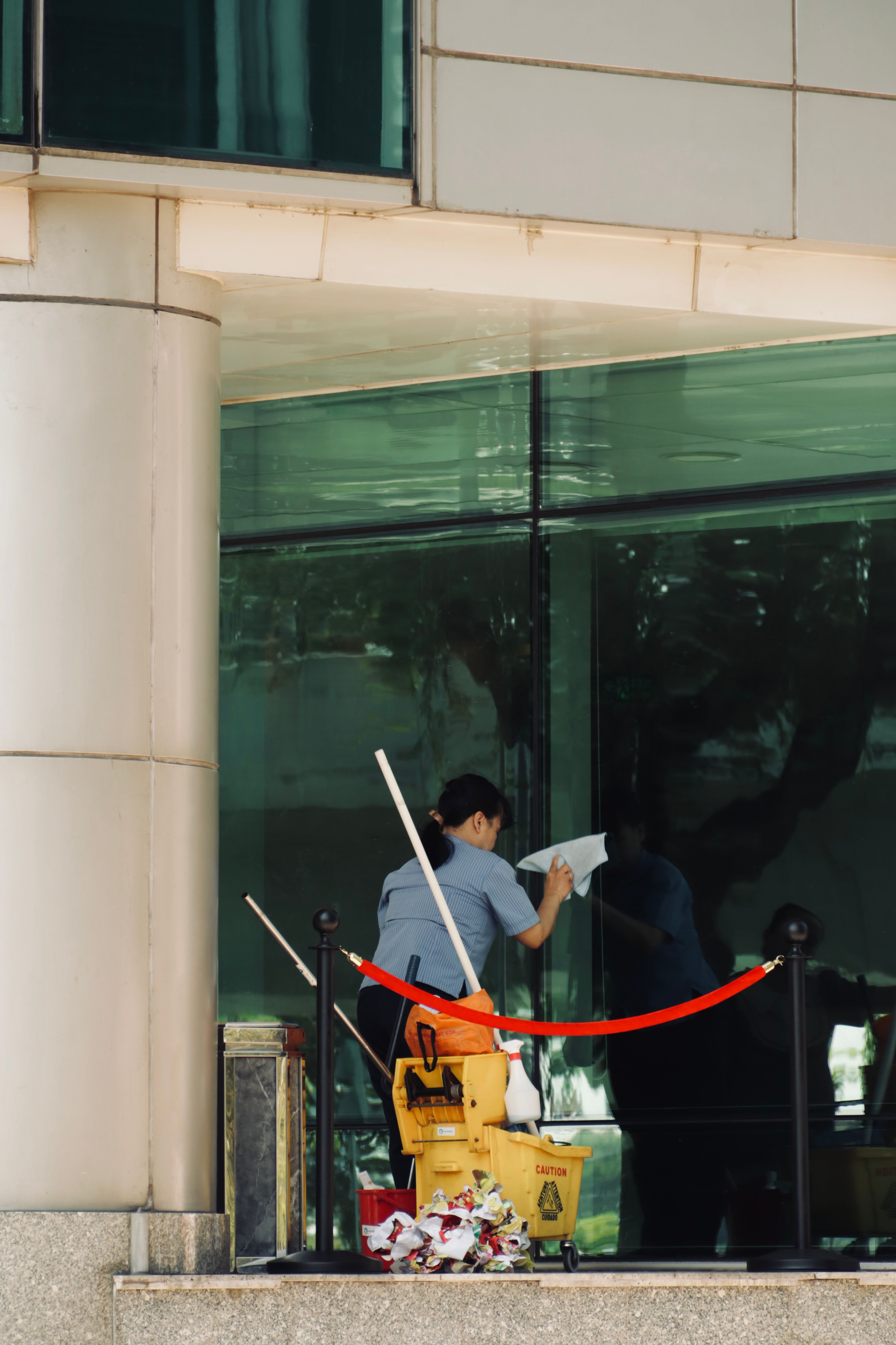 Uniformed cleaner wiping the glass facade of a commercial office building in Singapore
